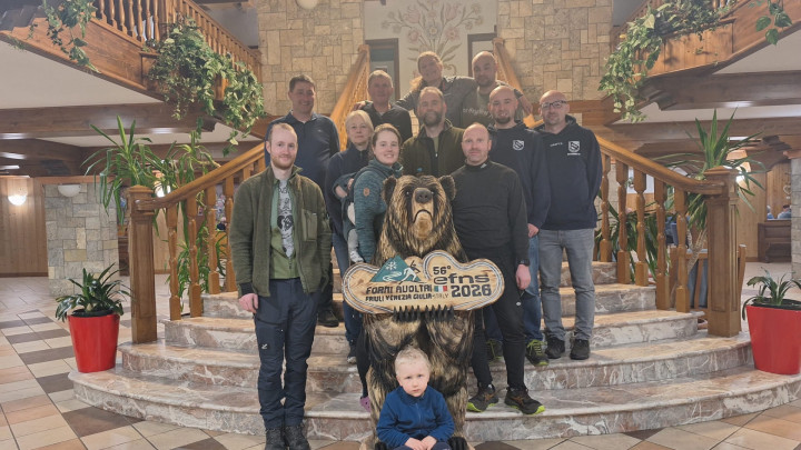 Gruppenbild auf der Treppe im Sporthotel Bella Italia. Der Bär wurde während dem Wettkämpfen mit der Kettensäge geschnitzt.